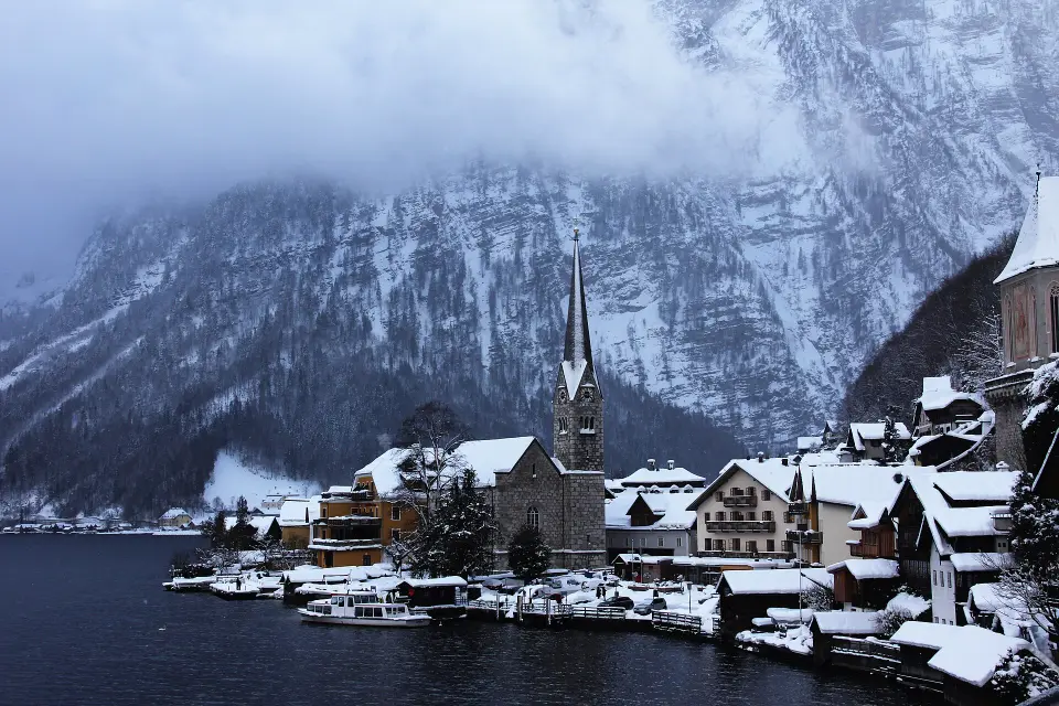 Satul Hallstatt sub zăpadă, cu biserica și munții în spate