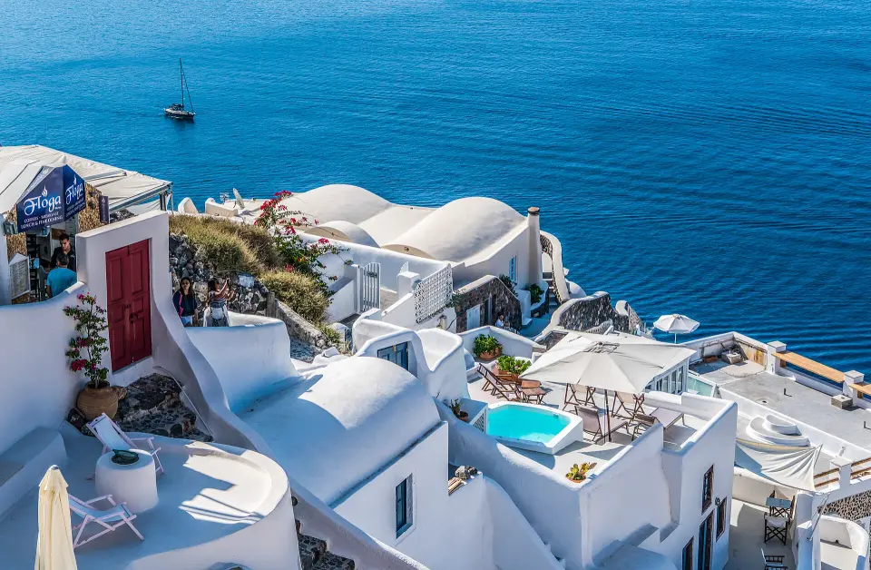 Case albe cu cupole albastre pe stâncile din Santorini
