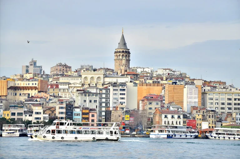 Turnul Galata deasupra caselor colorate, văzut de pe apă